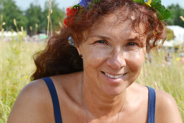 Happy krásná rusovláska žena s květinami ve vlasech v její let smilling venku — Stock fotografie