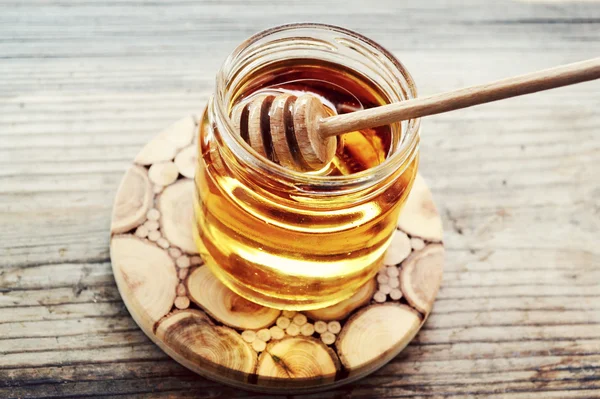 Golden honey with honeystick. cinnamon and anise stars on wooden table — Stock Photo, Image