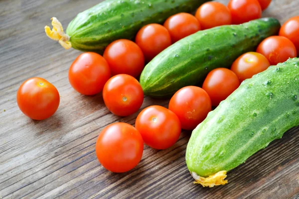 Het concept van gezond eten met organische komkommer en cherry tomaten op houten tafel — Stockfoto
