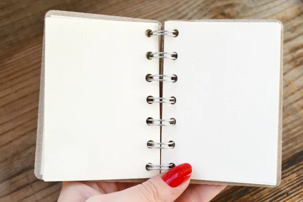 Mooie hand met rode nagels houden een lege retro spiraal notebook met oud papier — Stockfoto