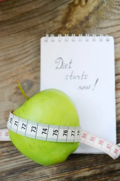 Ruokavalio käsite vihreä omena, muistikirja ja mittanauha puinen pöytä — kuvapankkivalokuva