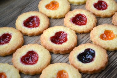 Ahşap masa üzerinde kalp şeklinde reçelli ev yapımı kurabiye