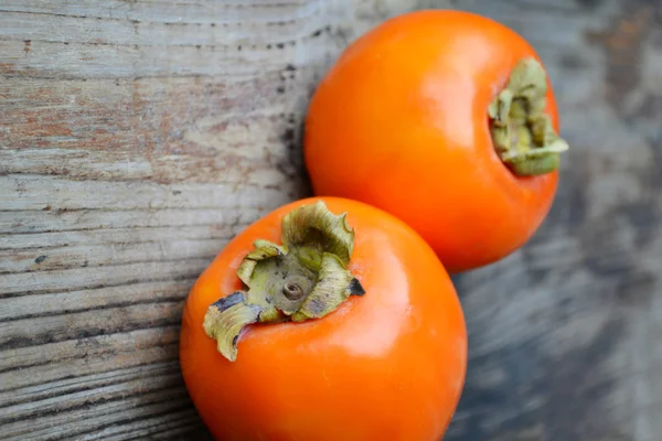 Pyszne pomarańczowy persimmons na drewnianym stole — Zdjęcie stockowe