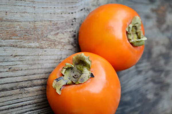 Heerlijke oranje kaki op houten tafel — Stockfoto