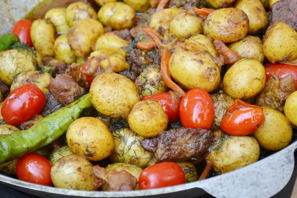 Duży kocioł z pieczone ziemniaki, mięso i pomidory — Zdjęcie stockowe