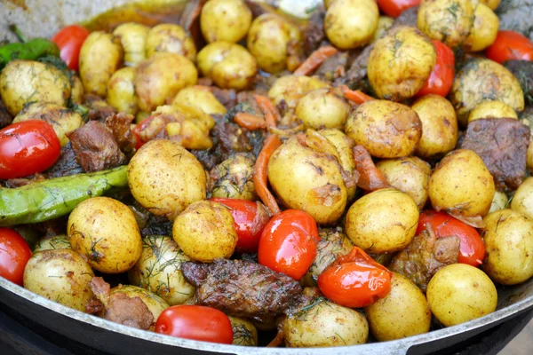 Großer Kessel mit Bratkartoffeln, Fleisch und Tomaten — Stockfoto