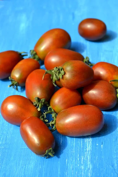 Tomates grandes de color rojo oscuro sobre fondo azul brillante — Foto de Stock