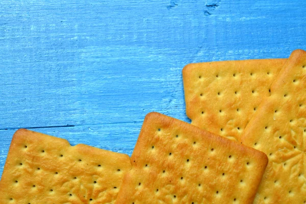 Tasty salty crackers on blue wooden background — Stock Photo, Image