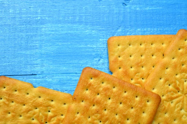 Tasty salty crackers on blue wooden background — Stock Photo, Image