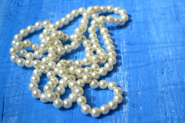 Un collier de perles sur table en bois bleu — Photo