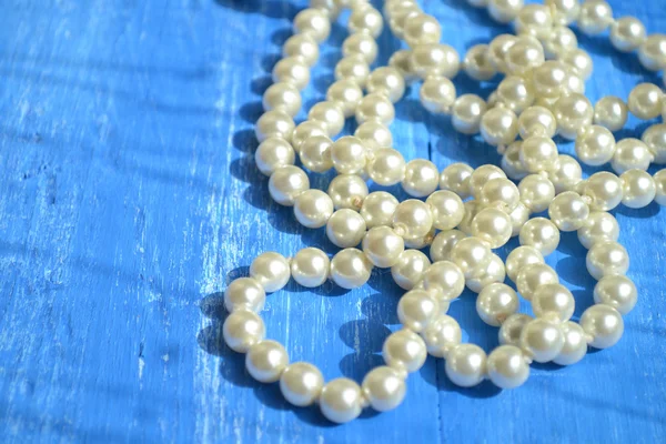 Un collier de perles sur table en bois bleu — Photo