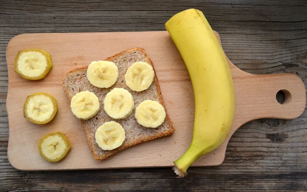 Gesundes Toast mit Banane auf Holzbrett — Stockfoto