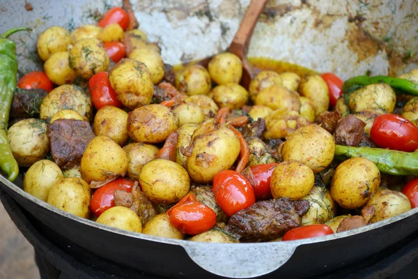 Duży kocioł z pieczone ziemniaki, mięso i pomidory — Zdjęcie stockowe