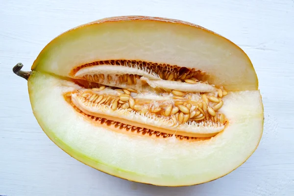 Tasty orange melon cut in half on white wooden board — Stock Photo, Image