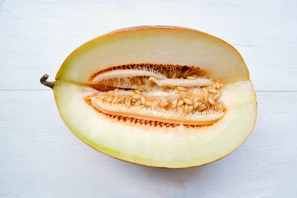 Appelsinaktig melon delt i to på hvitt trebord – stockfoto