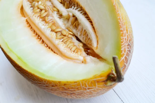 Tasty orange melon cut in half on white wooden board — Stock Photo, Image