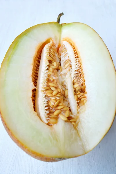 Tasty orange melon cut in half on white wooden board — Stock Photo, Image