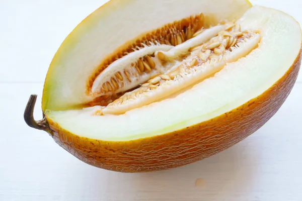 Sabroso melón naranja cortado por la mitad sobre tabla de madera blanca — Foto de Stock