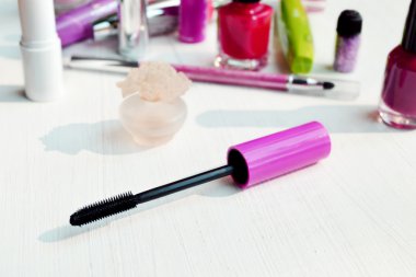 Pembe maskara sopa, göz kalemi, ruj, kalem ve beyaz tuvalet masasının üzerinde diğer kozmetik