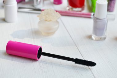 Pembe maskara sopa, göz kalemi, ruj, kalem ve beyaz tuvalet masasının üzerinde diğer kozmetik