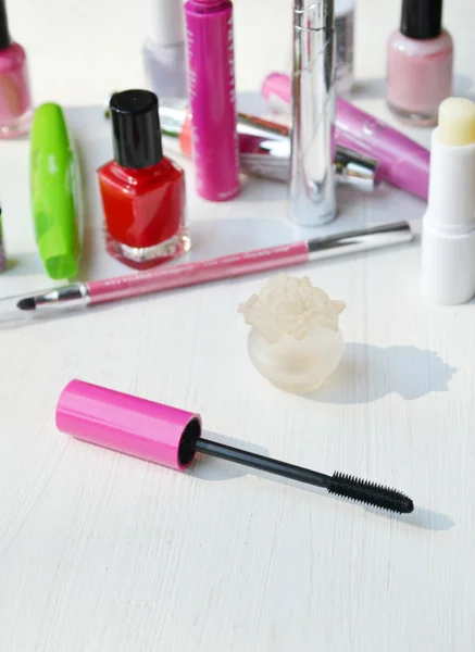 Kij różowy tusz do rzęs, eyeliner, szminka, ołówek i inne kosmetyki na biała toaletka — Zdjęcie stockowe