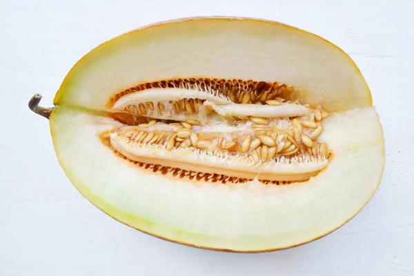 Tasty orange melon cut in half on white wooden board — Stock Photo, Image