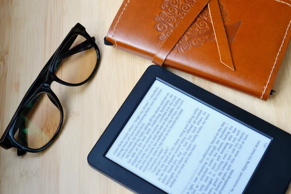 Lecteur noir avec lunettes de lecture et un vieux carnet en cuir recouvert sur table en bois — Photo