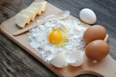 yumurta, tereyağı ve tahta kaşık yemek kartı üzerindeki beyaz un