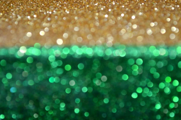 Яркий и абстрактный размытый зеленый фон с золотым мерцающим блеском — стоковое фото