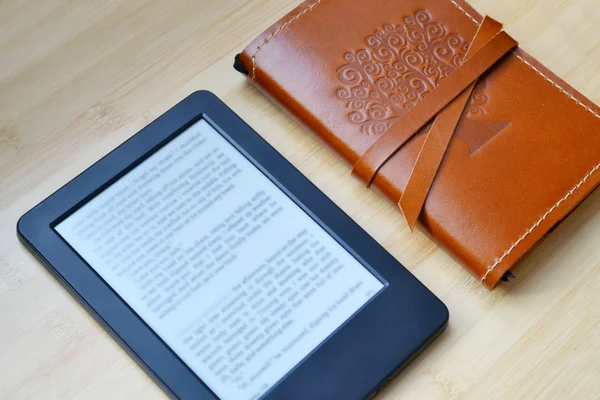 Ereader czarny z czytanie okulary i Starego notebooka w skórzane pokrycie na drewnianym stole — Zdjęcie stockowe