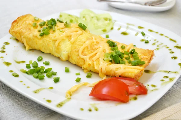 Omelete saborosa com queijo e cebola verde servido com tomate em um prato branco — Fotografia de Stock