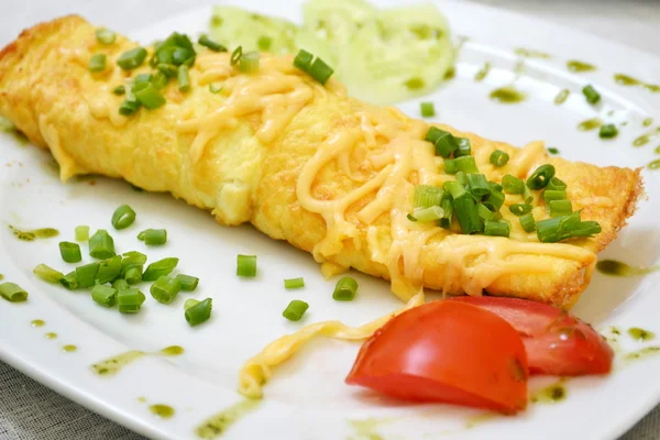 Leckeres Omelett mit Käse und grünen Zwiebeln serviert mit Tomaten auf einem weißen Teller — Stockfoto