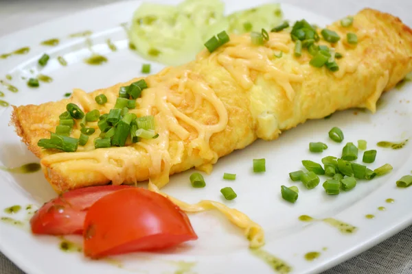 Leckeres Omelett mit Käse und grünen Zwiebeln serviert mit Tomaten auf einem weißen Teller — Stockfoto