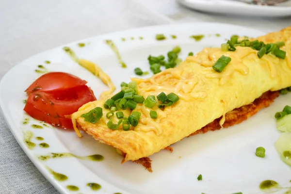 Omelete saborosa com queijo e cebola verde servido com tomate em um prato branco — Fotografia de Stock