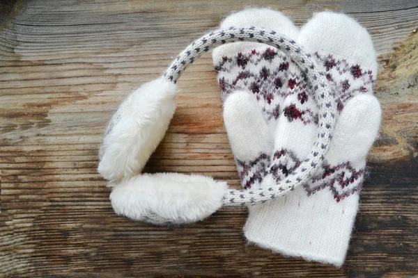 Soft woolen mittens with winter headphones on wooden table — Stock Photo, Image