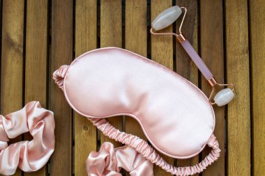 Yumuşak ipeksi pembe uyku maskesi, saç tokası ve kuvars silindirli.