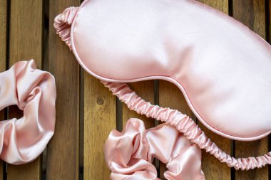 Yumuşak ipeksi pembe uyku maskesi, saç tokası ve kuvars silindirli.