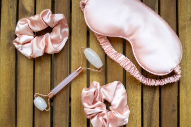 Yumuşak ipeksi pembe uyku maskesi, saç tokası ve kuvars silindirli.