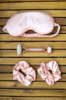 Yumuşak ipeksi pembe uyku maskesi, saç tokası ve kuvars silindirli.