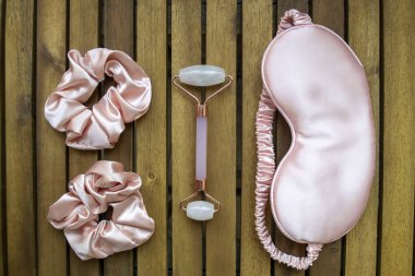 Yumuşak ipeksi pembe uyku maskesi, saç tokası ve kuvars silindirli.