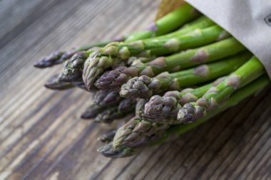 Tahta arka planda taze, yeşil, sağlıklı, çiğ kuşkonmaz.