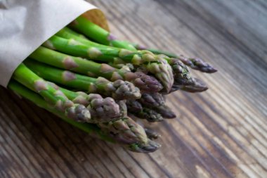 Tahta arka planda taze, yeşil, sağlıklı, çiğ kuşkonmaz.