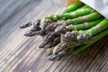 Tahta arka planda taze, yeşil, sağlıklı, çiğ kuşkonmaz.