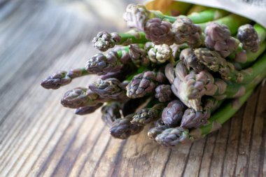 Tahta arka planda taze, yeşil, sağlıklı, çiğ kuşkonmaz.