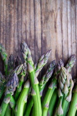 Tahta arka planda taze, yeşil, sağlıklı, çiğ kuşkonmaz.