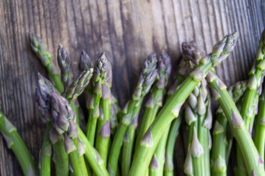 Tahta arka planda taze, yeşil, sağlıklı, çiğ kuşkonmaz.