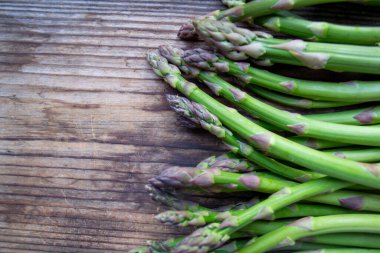 Tahta arka planda taze, yeşil, sağlıklı, çiğ kuşkonmaz.