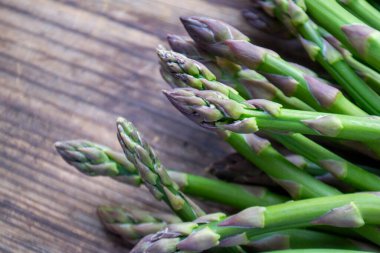 Tahta arka planda taze, yeşil, sağlıklı, çiğ kuşkonmaz.
