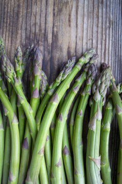 Tahta arka planda taze, yeşil, sağlıklı, çiğ kuşkonmaz.