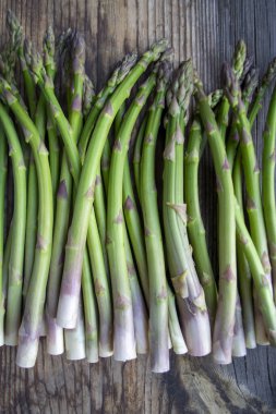 Tahta arka planda taze, yeşil, sağlıklı, çiğ kuşkonmaz.